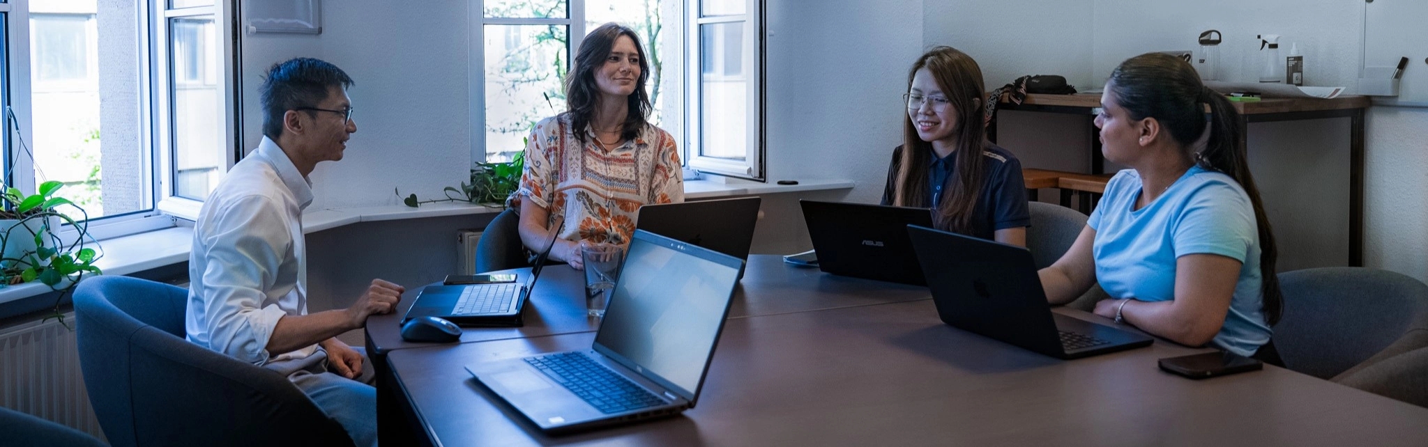Nachhaltigkeitsmanagerin Peigi Rodan sitzt zusammen mit Studenten an einem Tisch, alle arbeiten mit Laptops.